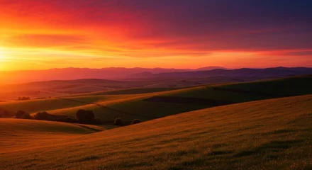Fototapete Photo of a vibrant sunset paints the sky in hues of orange and red over the rolling green hills, creating a peaceful and idyllic landscape © Tae-Wan