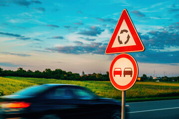 Roundabout ahead and no overtaking traffic signs by the road