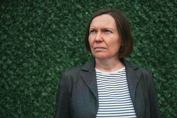 Portrait of serious confident business woman standing against the artificial grass wall