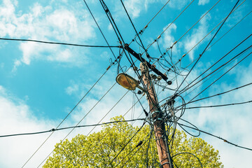 Old wooden lamp post with street light and messy electrical wires