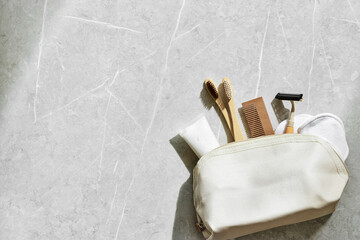 Beige fabric toiletry bag with eco-friendly personal care essentials on marble table. Bag with...