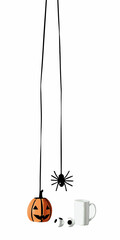 Halloween decor featuring a pumpkin, spider hanging from string, eyeballs and a white mug on white