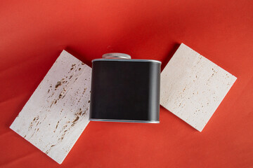 Black can for packaging with stylish props on red background.