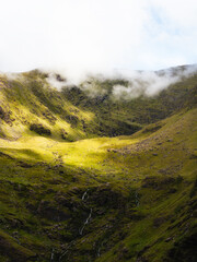 A valley within Carrauntoohil is covered in green vegetation, with sparse waterfalls cascading down...