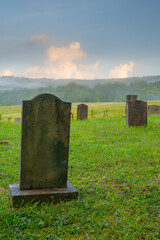 The Cades Cove Methodist church cemetery in the Great Smoky Mountains, with fog and mountains in...