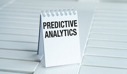 A white spiral notebook with the word predictive analytics written on it