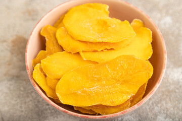 Dried Mango in ceramic bowl on brown concrete. Side view, selective focus