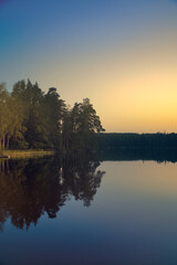 Atmospheric lake in Sweden at sunset with reflection of the trees.