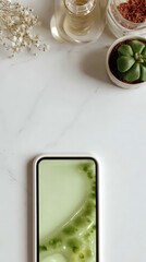 Smartphone with green abstract display on marble surface with succulent and skincare items