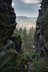 View into a rocky gorge with a wooded valley and hills in the background
