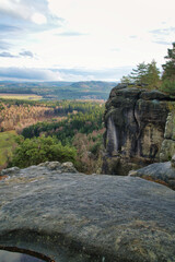 Majestic rock formation rises above wooded valley under blue sky