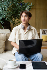 Non binary Asian student man sitting in modern coffee shop using laptop computer