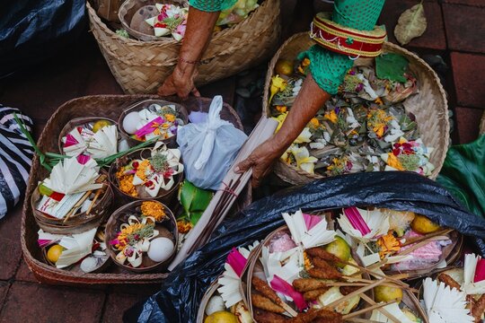 A Balinese woman prepares offerings, called Canang Sari, in woven baskets. These are daily offerings to the gods, with flowers, food, and incense in Ubud, Bali, Indonesia