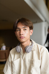 Non binary Asian student man sitting in modern coffee shop
