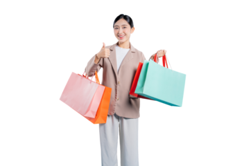 A happy and satisfied young Asian woman gives a thumbs-up gesture while holding colorful shopping bags, indicating approval and a great shopping experience, standing against a solid png background.

