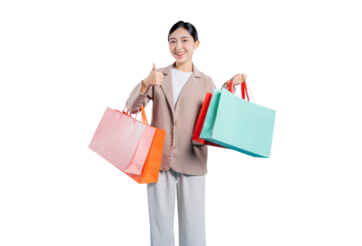 A happy and satisfied young Asian woman gives a thumbs-up gesture while holding colorful shopping bags, indicating approval and a great shopping experience, standing against a solid png background.
