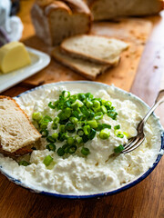 Cottage cheese with chives and bread on wooden table