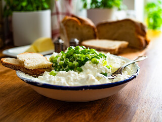 Cottage cheese with chives and bread on wooden table	