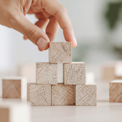 Close up hand and stack of wood block cube on the table.