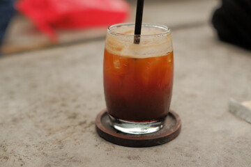 A glass of coffee with ice cubes in it. The coffee is brown and the ice cubes are white