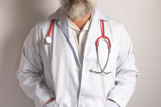 Doctor wearing white coat and red stethoscope with hands in pockets - Powered by Adobe
