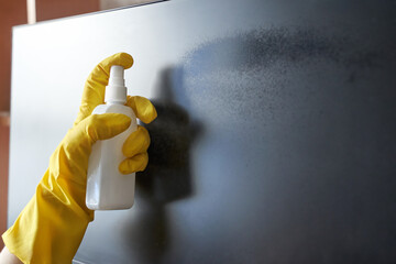 Person cleaning screen with spray bottle and yellow gloves for a streak free finish.