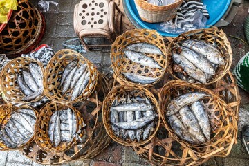 Fishmongers in Ubud, Bali, Indonesia sell dried fish in woven baskets at a local market. The fish...