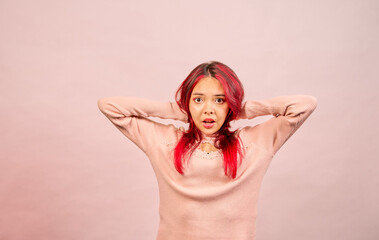 Young woman holding head showing frustration on pink background