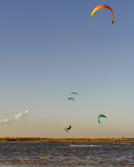 Kitesurfer gliding in coastal lagoon at golden hour with natural background