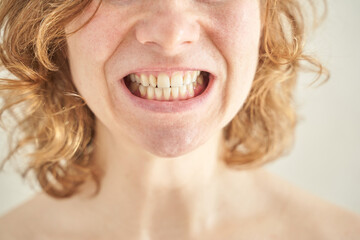 Close-up of young caucasian female smiling with curly hair and visible teeth.