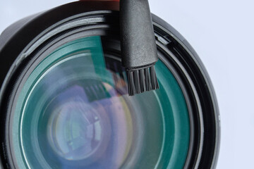 Close up of camera lens with cleaning brush on transparent surface with reflection.