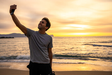 Smiling man taking selfie at the beach during golden sunset