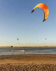 Kitesurfer gliding in coastal lagoon at golden hour with natural background