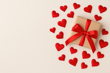 Romantic holiday backdrop featuring a gift box adorned with red hearts, viewed from above with space for text.