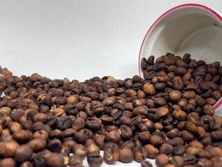 Brown coffee beans falling from cup isolated on white background