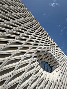 Los Angeles, California, USA - April 18, 2024: Low anlge view of unique honeycomb-like architectural design of The Broad Museum's facade with a window against blue sky