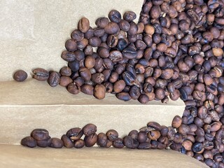 Dry brown black  roasted coffee beans on a brown paper texture background