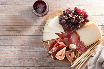 Charcuterie Board with Cheese, Grapes, Figs and wine on wooden table. Top view. Copy space