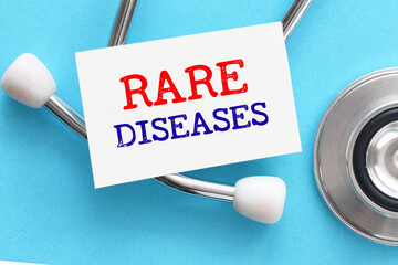 The words RARE DISEASES on a small piece of paper next to a stethoscope and blue background.