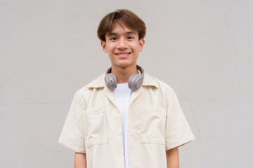 Non binary cute Asian young gay man portrait against studio background