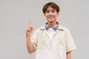 Non binary cute Asian young gay man showing and pointing to copy space