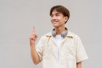 Non binary cute Asian young gay man showing and pointing to copy space