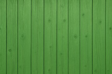 Fototapeta premium Surface of lush green wooden planks, featuring a fence with vertically aligned, brightly colored boards of varying sizes, showcasing cracks and knots in the background