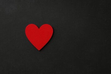 Dark background with a red heart from a top perspective and space for text