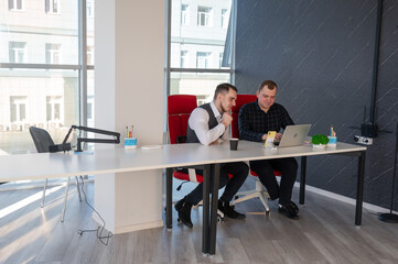 Two Caucasian men sitting at a table and discussing work. 