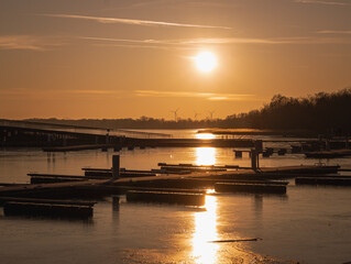 A peaceful sunset over the harbor in Senftenberg, Germany. The golden light reflects on the calm...