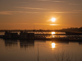 A peaceful sunset over the harbor in Senftenberg, Germany. The golden light reflects on the calm...