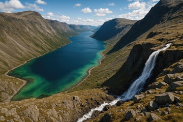 Naklejka premium Aerial perspective of a majestic mountain overlooking a vibrant blue and green fjord, with cascading waterfalls and rugged, barren terrain