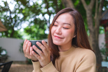 Portrait image of a woman holding and drinking coffee in the outdoors cafe