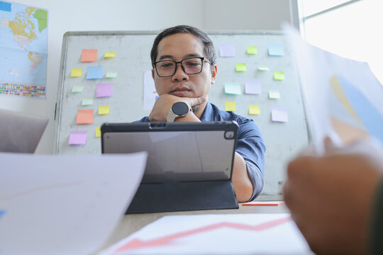 Thoughtful Businessman Analyzing Data On Digital Tablet